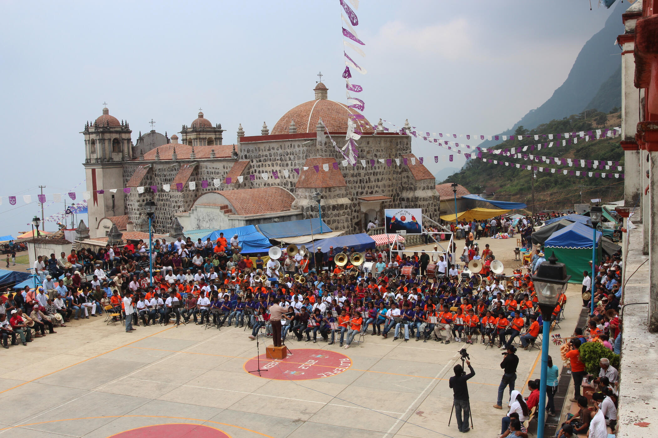 Mixe people's concert band in Oaxaca, Mexico Historic Catholic church with a large concert band performing on a basketball court in a mountainous village in Oaxaca, Mexico where indigenous Mixe communities gather for a yearly patron saint festival.